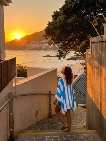 Woman wearing the blue and white Ziptique zipper towel heading down to the beach at sunset